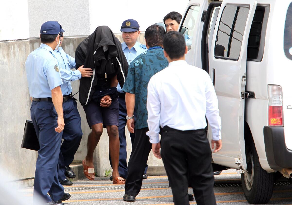 Former U.S. Marine Kenneth Shinzato is escorted by police officers from Uruma Police Station in Uruma, Okinawa, southwestern Japan on Friday.