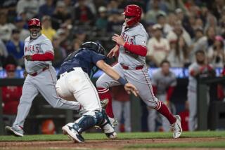 Los Angeles Angels' Brandon Drury, right, runs past Seattle Mariners catcher Cal Raleigh.