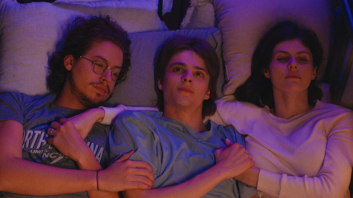 Three friends lie together in bed.