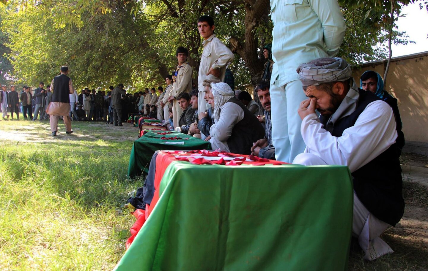 Mourning relatives gather beside the flag-draped coffins of schoolgirls killed in a stampede after the earthquake struck in Takhar province.