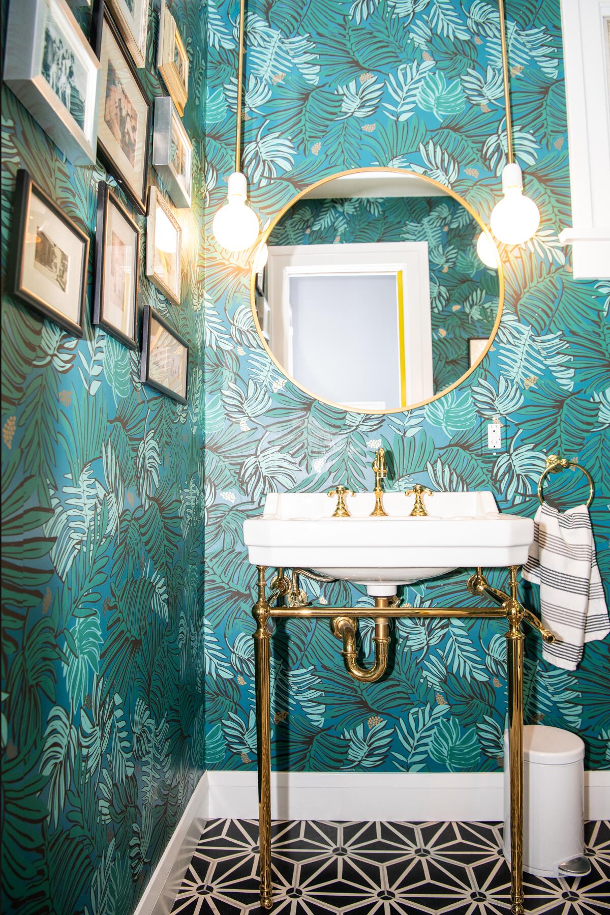 A salon wall in the powder room. The blue leaf-covered wallpaper is by Justina Blakeney.