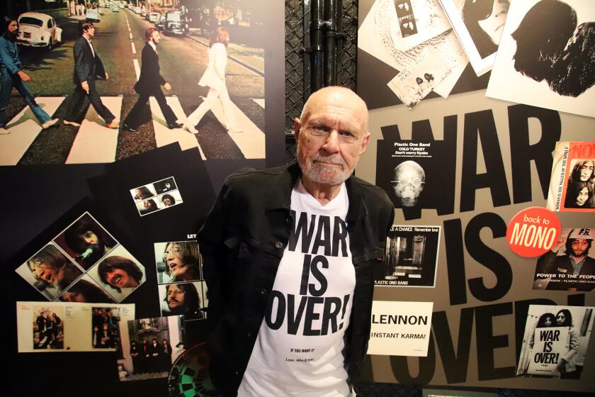 John Kosh is an iconic album cover designer who is best known for working with the Beatles, The Rolling Stones, and the Who, poses for a picture in front of the some of his must famous album covers, the Beatles Abbey Road and Let it Be during an exhibition celebrating his artistic achievements, the Art of Music Experience at the Orange County Fair in Costa Mesa on Saturday, August 3, 2024. (Photo by James Carbone)