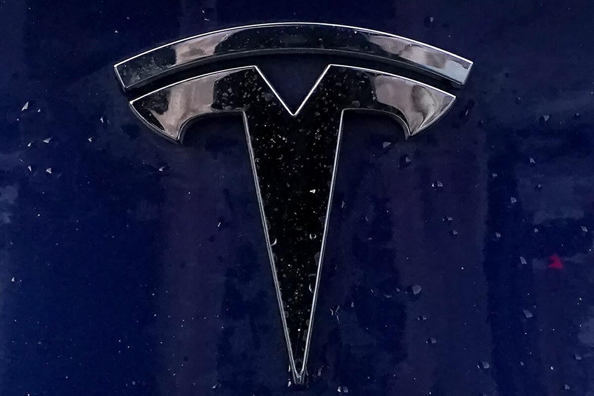 A Tesla electric vehicle emblem is affixed to a passenger vehicle 
