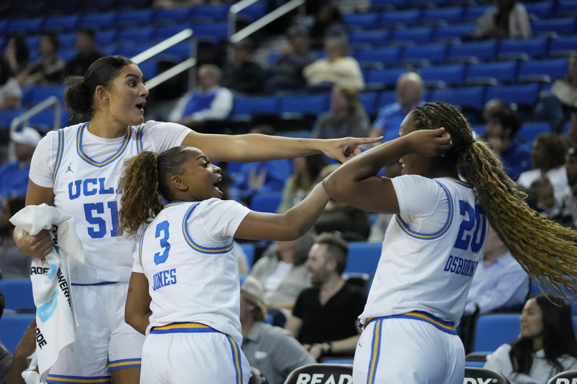 UCLA center Lauren Betts, guard Londynn Jones and guard Charisma Osborne celebrate on the sideline during a win