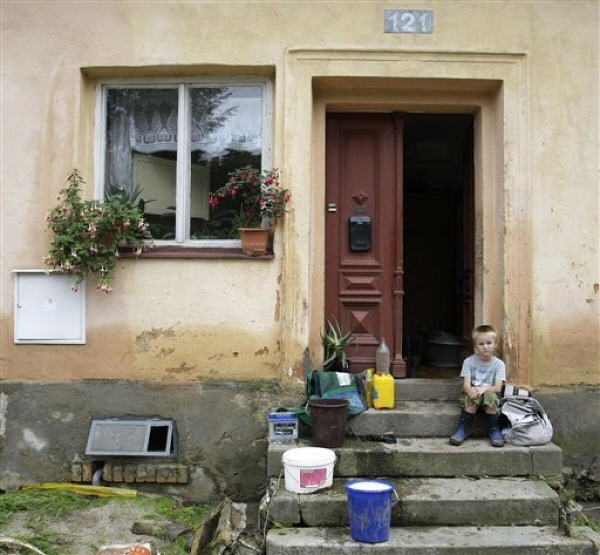 A young boy sits in front of a house damaged in flash floods in the village of Hermanice, Czech Republic, Sunday, Aug. 8, 2010. The flooding has struck an area near the borders of Poland, Germany and the Czech Republic. (AP Photo/Petr David Josek)