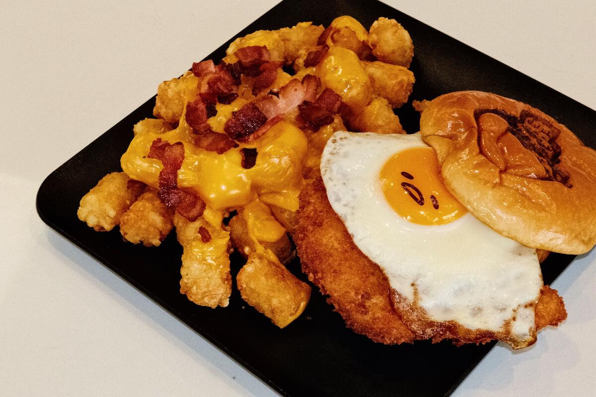A photo of an egg-topped katsu sandwich with tots on a white table at The Gudetama Cafe in Buena Park