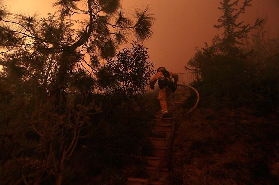 A Navy firefighter climps the backyard stairs at a home on Via Pluma as the Springs fire threatens hillside homes in Newbury Park.