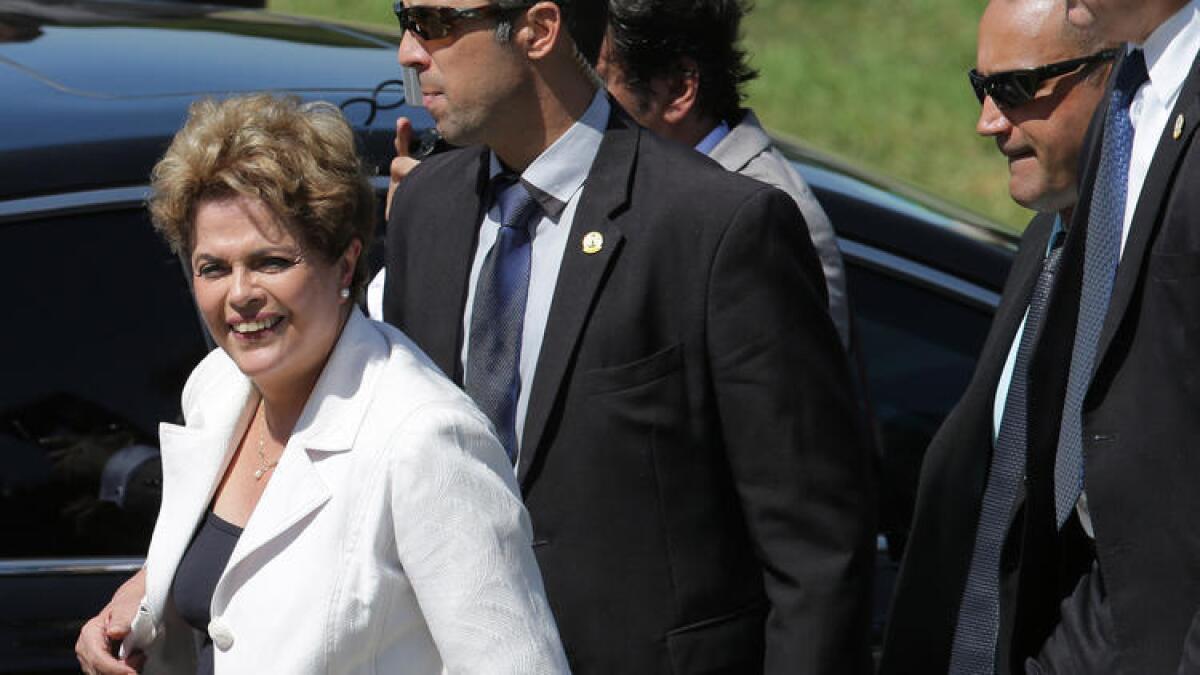 La presidente de Brasil, Dilma Rousseff, rodeada de su equipo de seguridad, deja el palacio presidencial Planalto, este jueves.