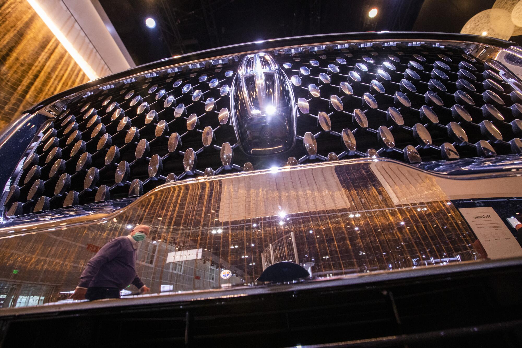 An automotive enthusiast is reflected in the grille of a 2022 Lincoln Navigator at the Los Angeles Auto Show.