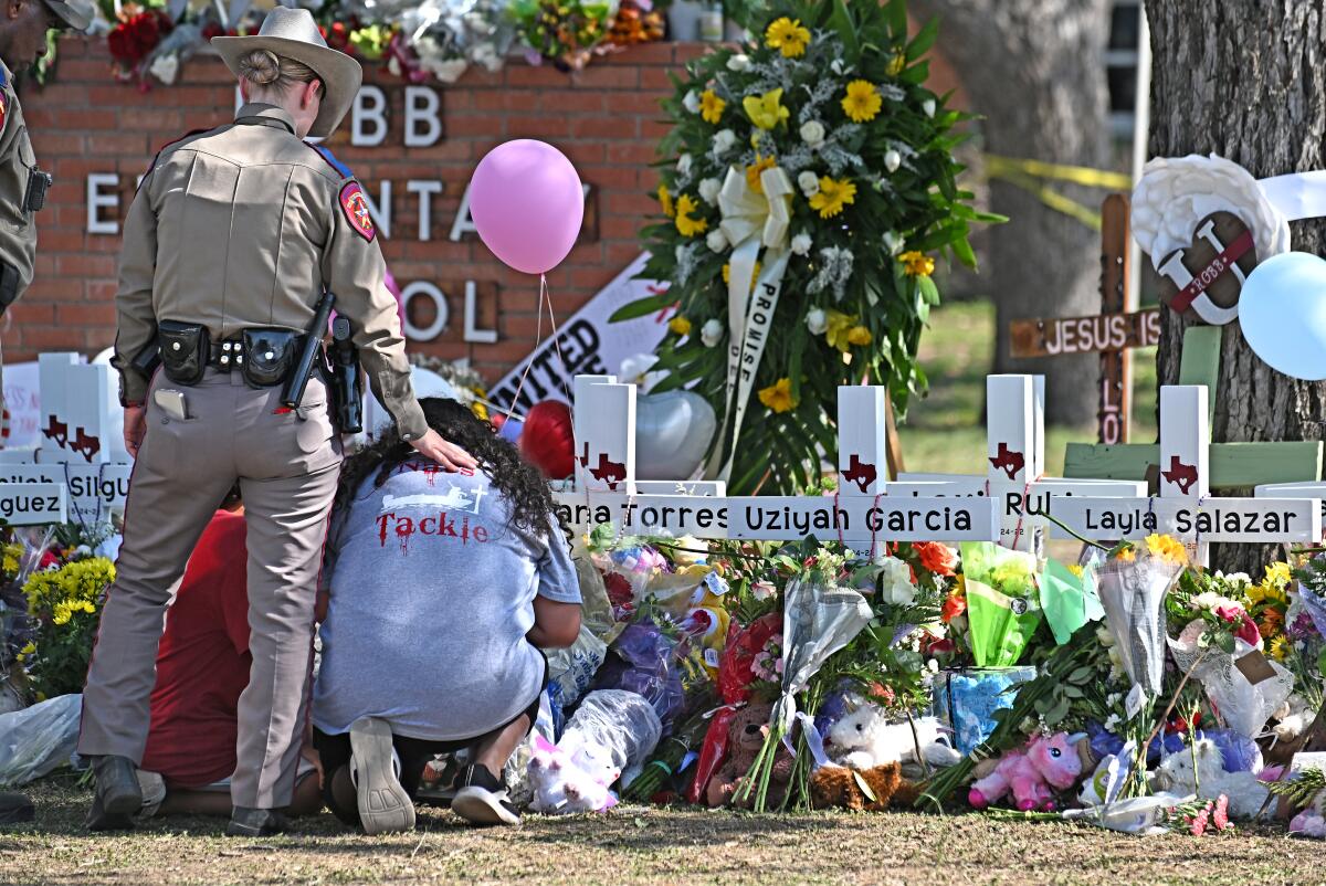 A police officer comforts family members at a memorial outside Robb Elementary School in Uvalde, Texas.