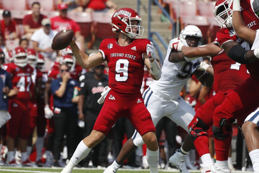 Fresno State quaterback Jake Haener throws a pass past Connecticut defenders.