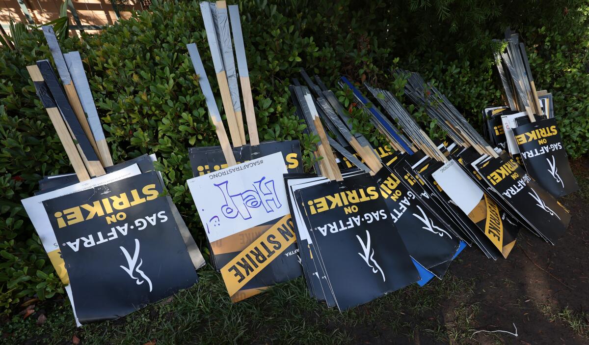 "SAG-AFTRA on strike" picket signs upside down against bushes 