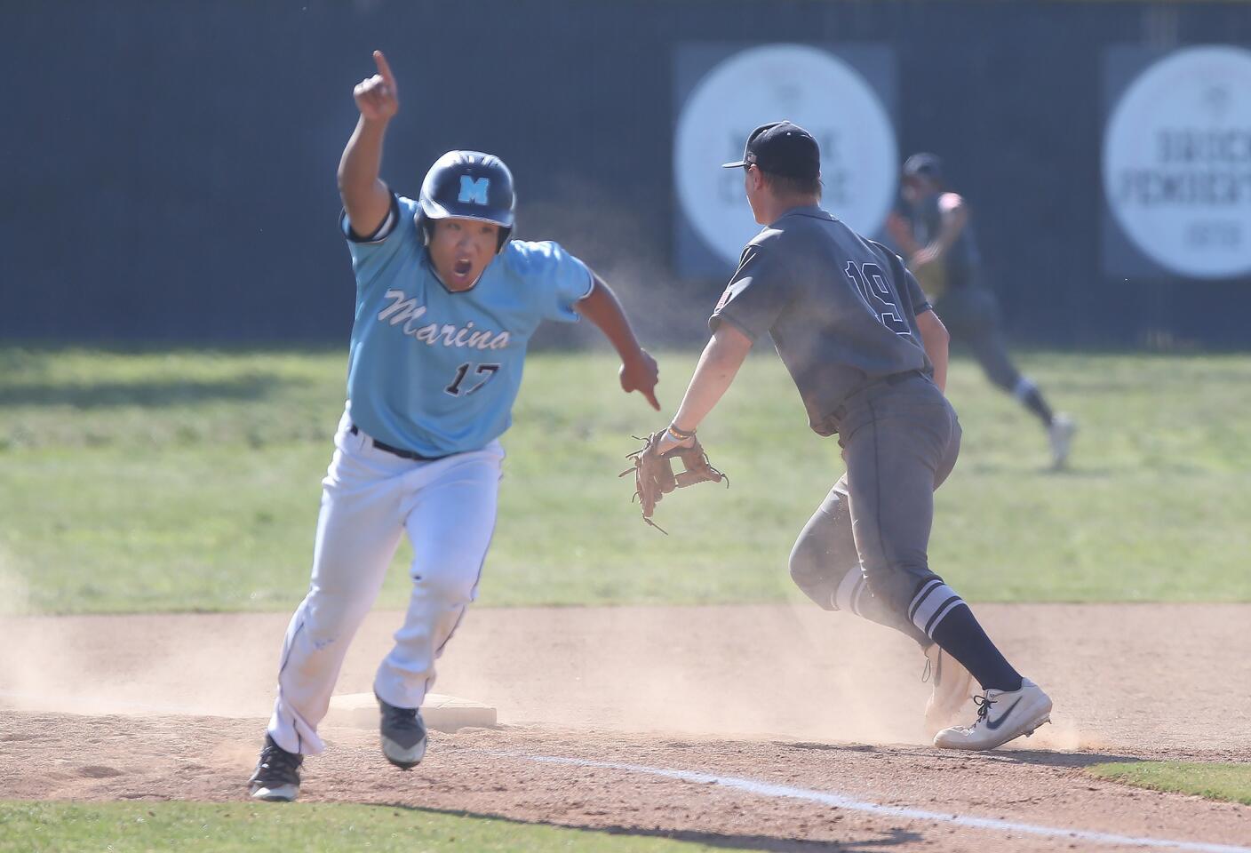 Marina High's Ryan Sueki heads home to score as a hit goes down the third-base line in a Wave League game at home against Newport Harbor on Tuesday.