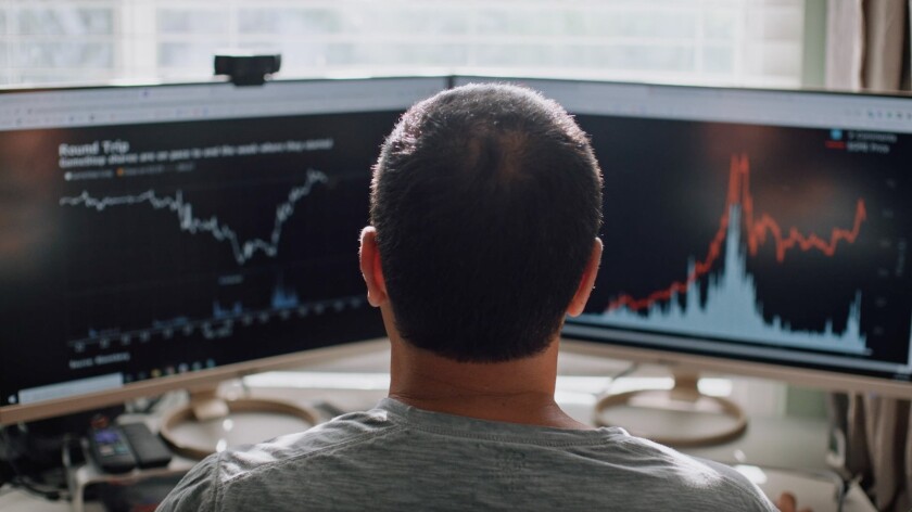 The back of a man's head as he faces two computer screens in the documentary "GameStop: Rise of the Players."