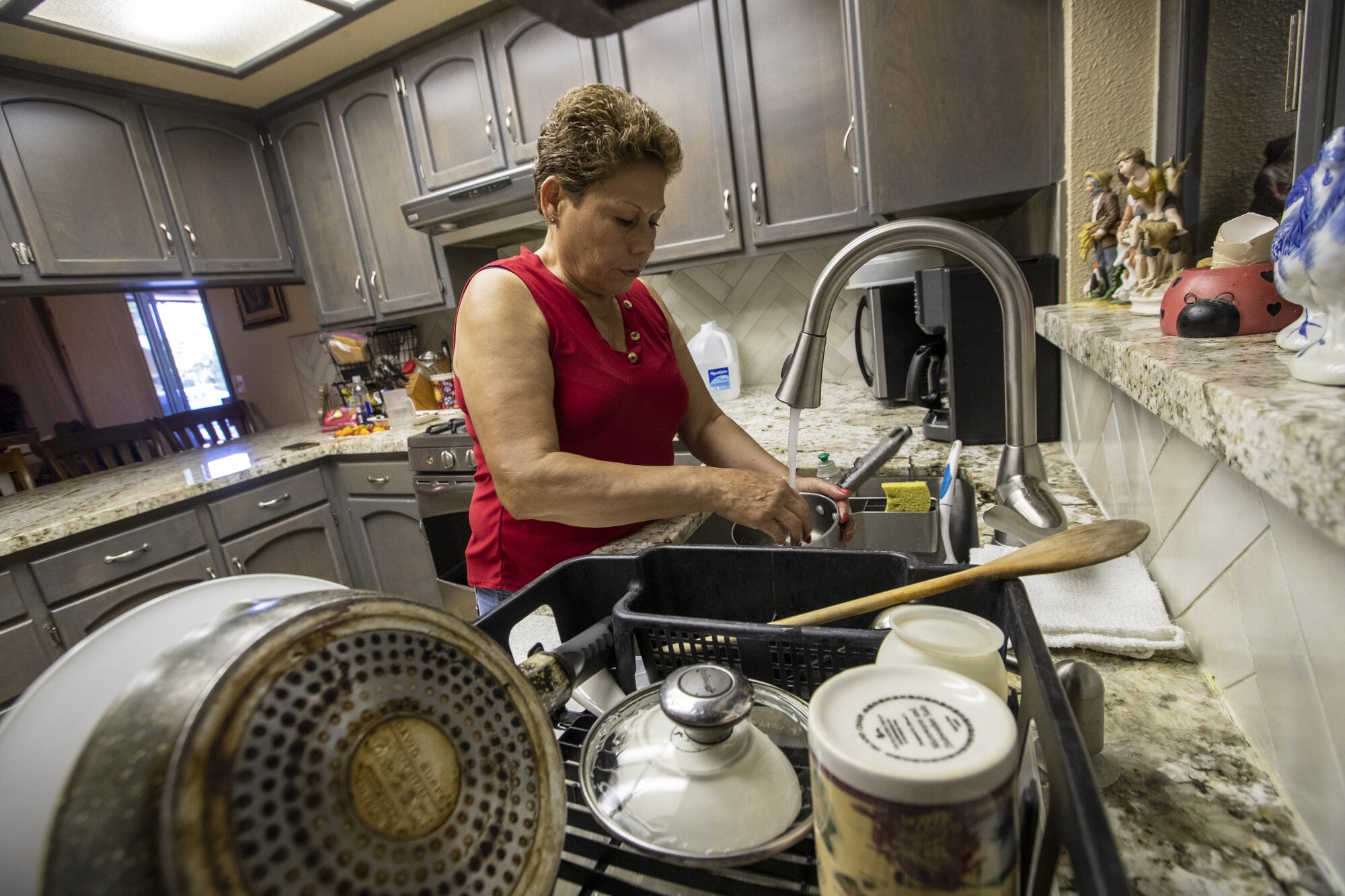 Maria Olivera, who is living with chromium and arsenic in her well, washes dishes at home.