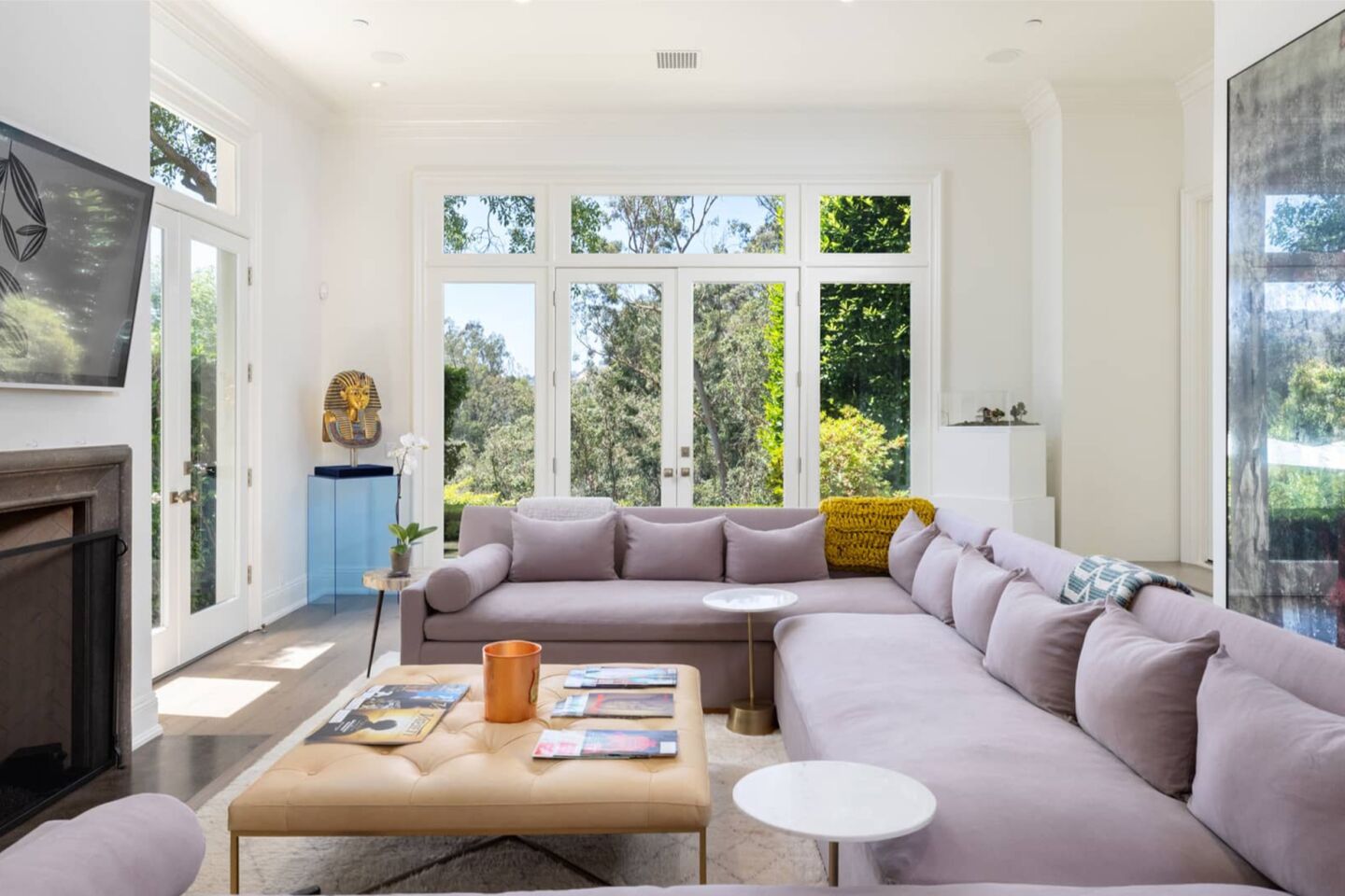 The living room is furnished and has windows overlooking greenery.
