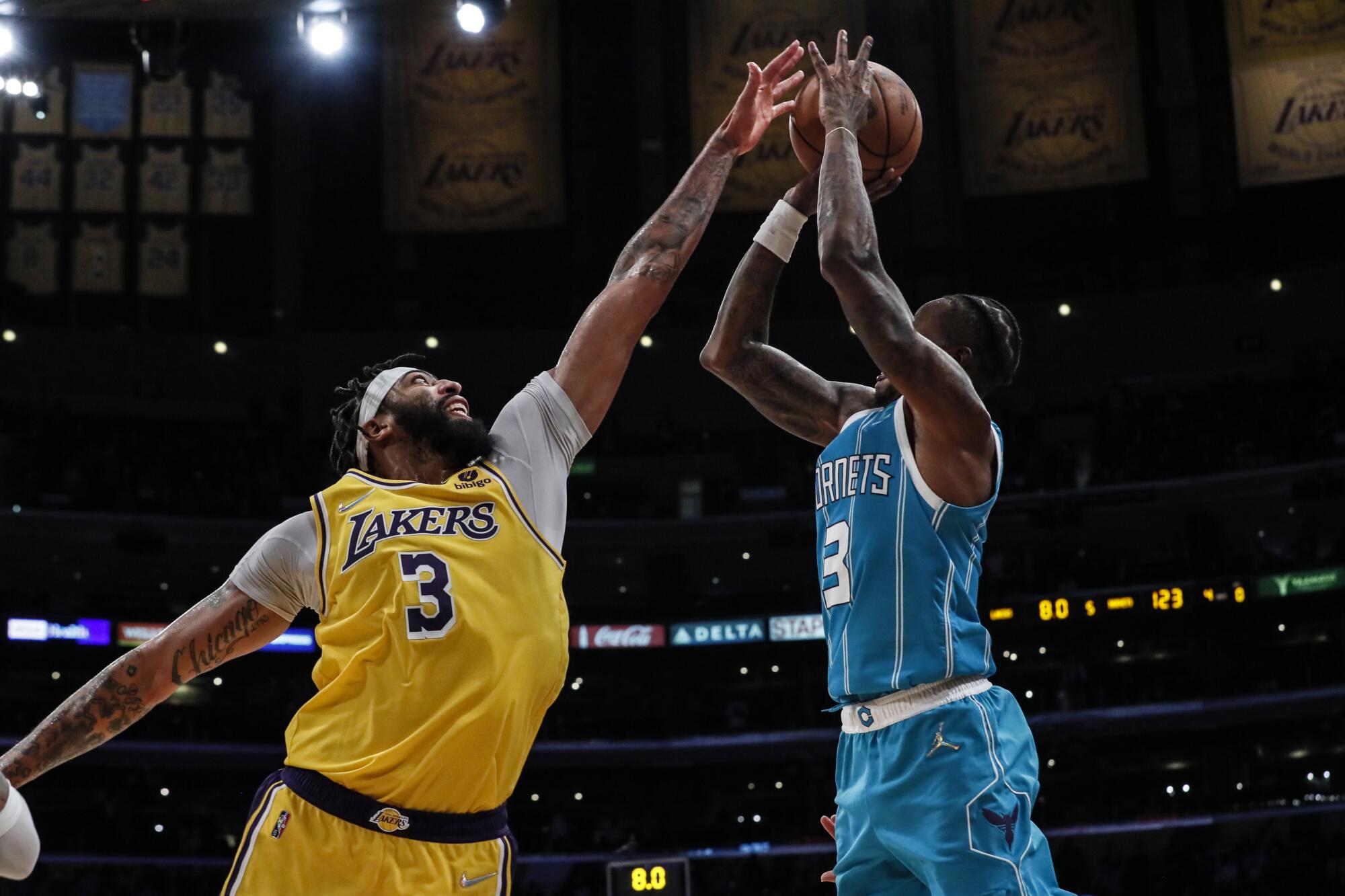 Lakers forward Anthony Davis extends his left arm as he tries to block a jump shot by Hornets guard Terry Rozier.