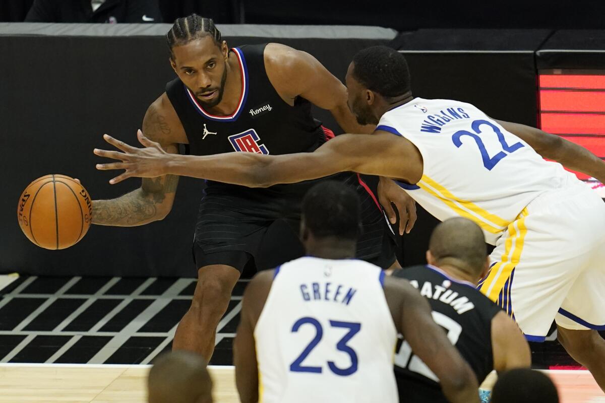 Clippers forward Kawhi Leonard passes next to Golden State Warriors forward Andrew Wiggins.