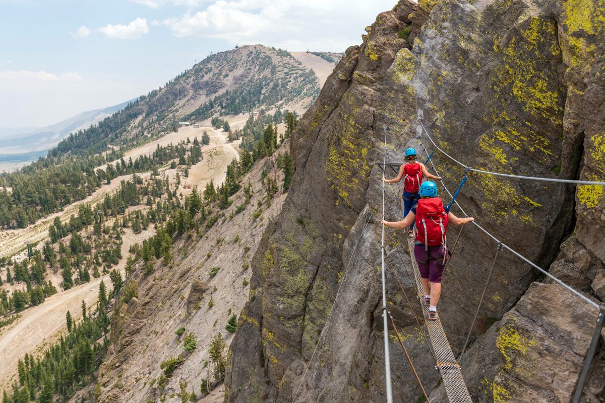 People walk on a narrow suspended plank with handholds at Mammoth Mountain's Adventure Center.
