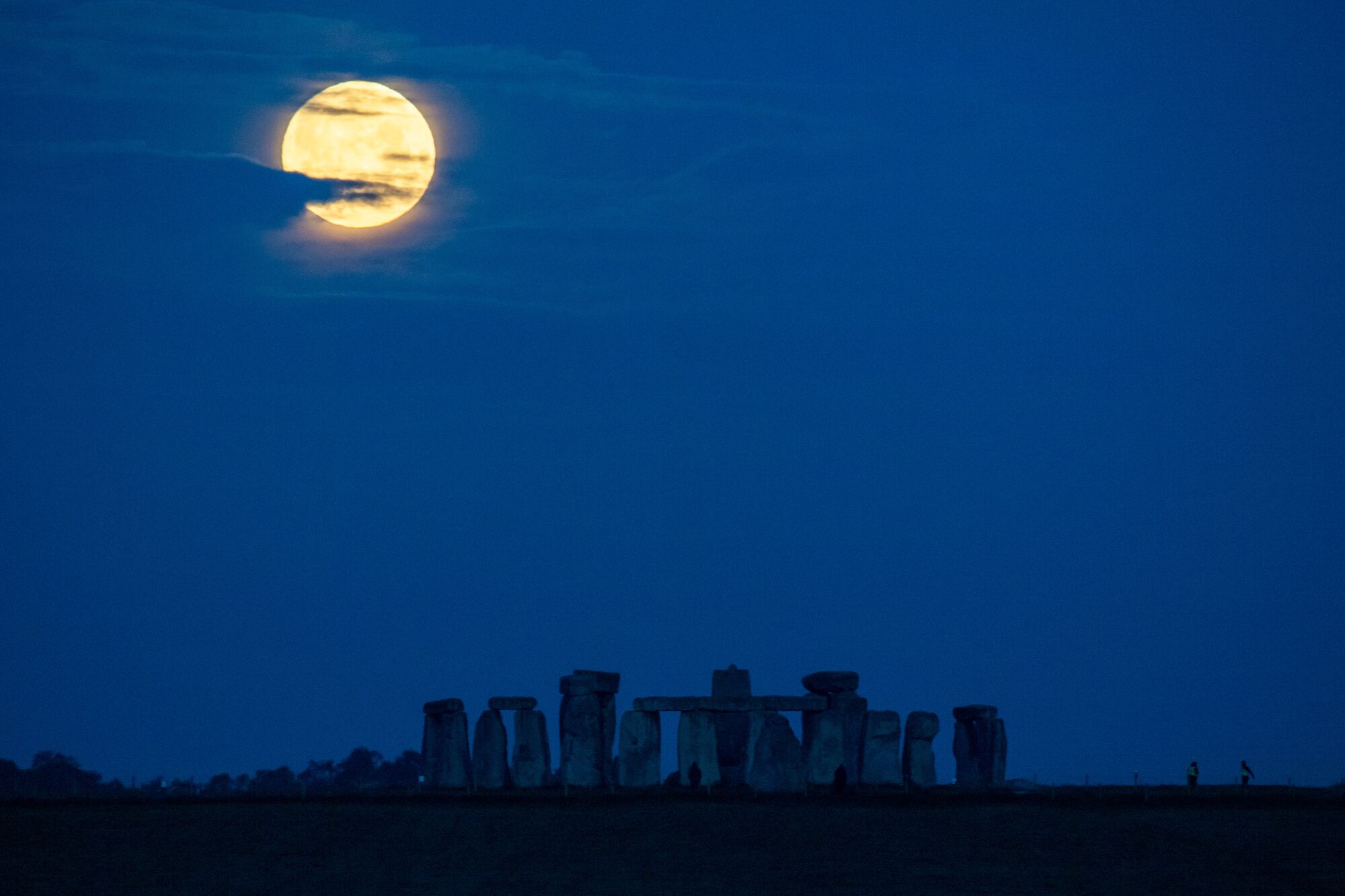 The super flower blood moon sets over the silhouette of the stones of Stonehenge
