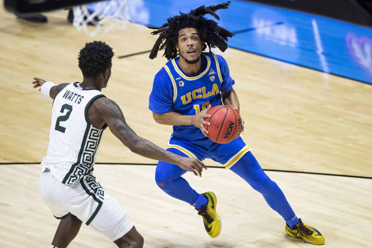 UCLA's Tyger Campbell, right, looks to shoot in front of Michigan State's Rocket Watts.