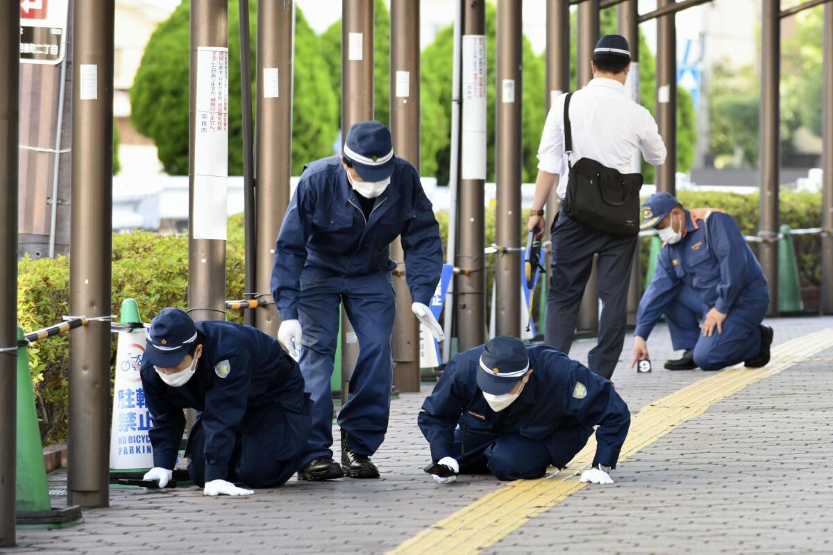 Police inspect a sidewalk near the site where former Japanese Prime Minister Shinzo Abe was fatally shot in Nara, western Japan, Wednesday, July 13, 2022. Abe was assassinated Friday while campaigning in Nara, western Japan. (Kyodo News via AP)