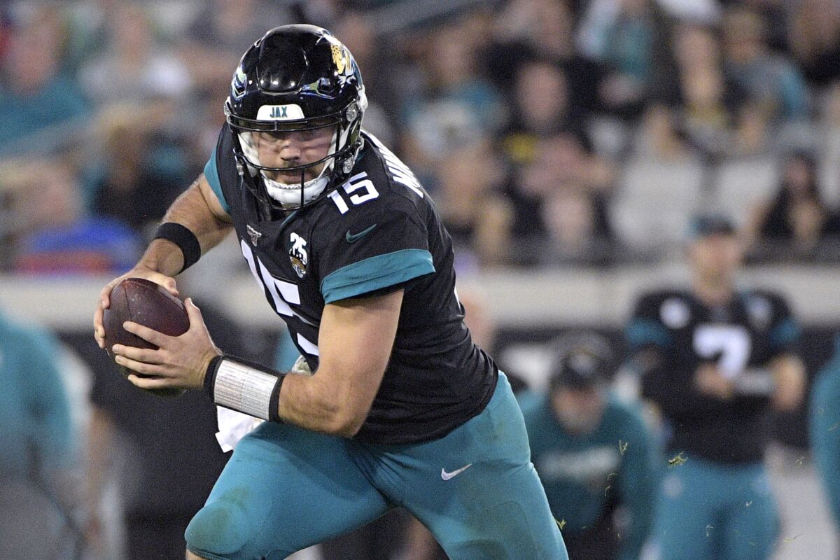 FILE - In this Dec. 29, 2019, file photo, Jacksonville Jaguars quarterback Gardner Minshew II (15) rolls out to throw a pass during the second half of an NFL football game against the Indianapolis Colts Sunday,, in Jacksonville, Fla. Minshew was ready for Jacksonville’s “first day of school.” Then Minshew got a call saying he had been in close contact with a teammate who tested positive for the coronavirus and would be forced to quarantine for two days. (AP Photo/Phelan M. Ebenhack, File)