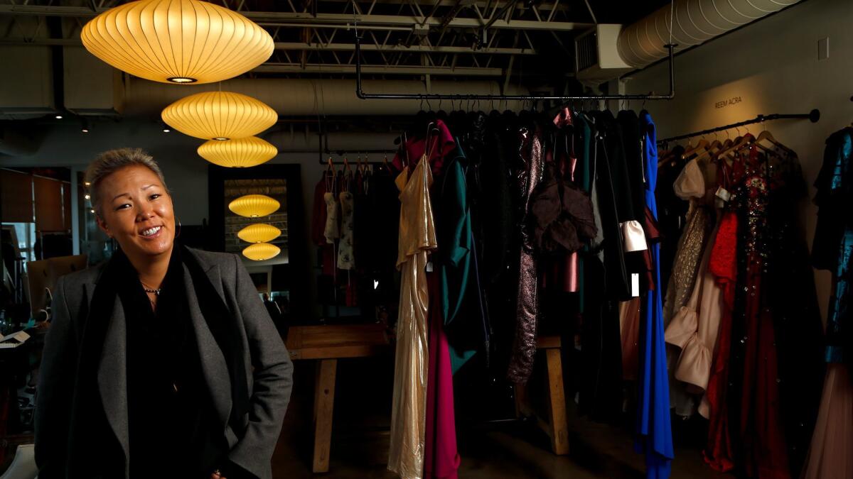 Stylist Jeanne Yang stands next to a rack of clothes.