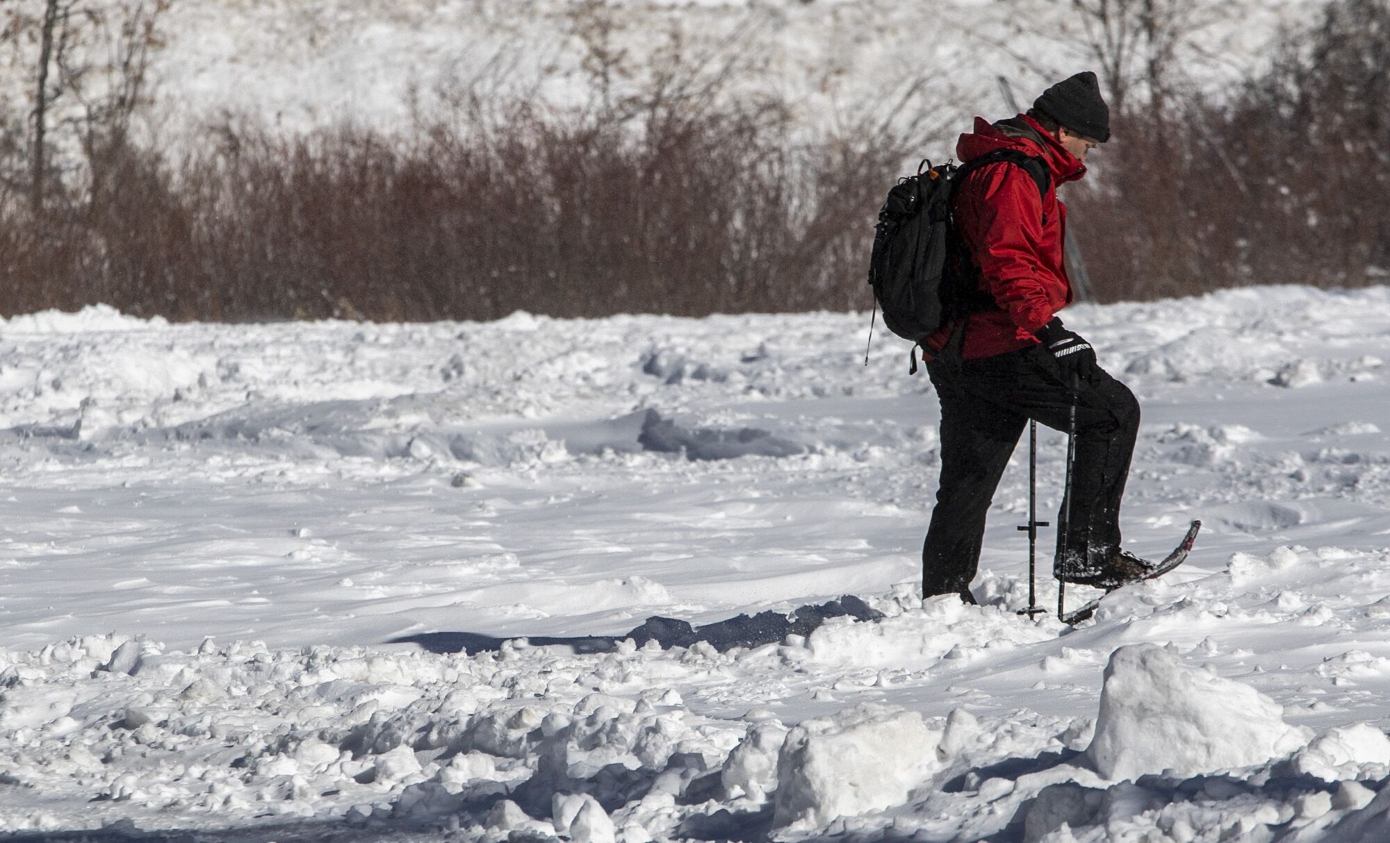 A snowshoer walks through fresh snow along a road in Big Bear Lake.