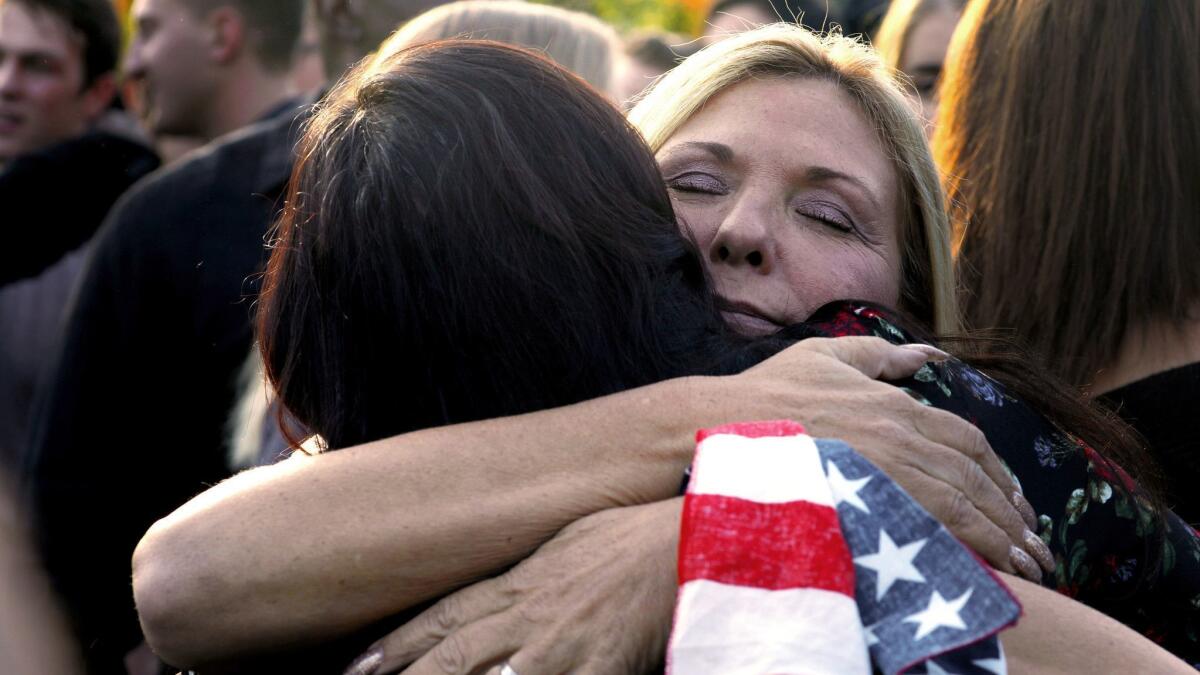 Wearing an American flag on her wrist, Laura Lynn Meek, right, mother of Justin Meek, is hugged outside Cal Lutheran University Samuelson Chapel after a memorial service for her son, who was killed in the Borderline shooting.