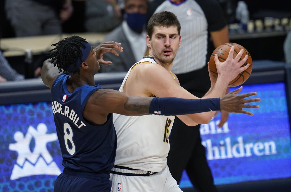 Denver Nuggets center Nikola Jokic looks to pass the ball as Minnesota Timberwolves forward Jarred Vanderbilt.