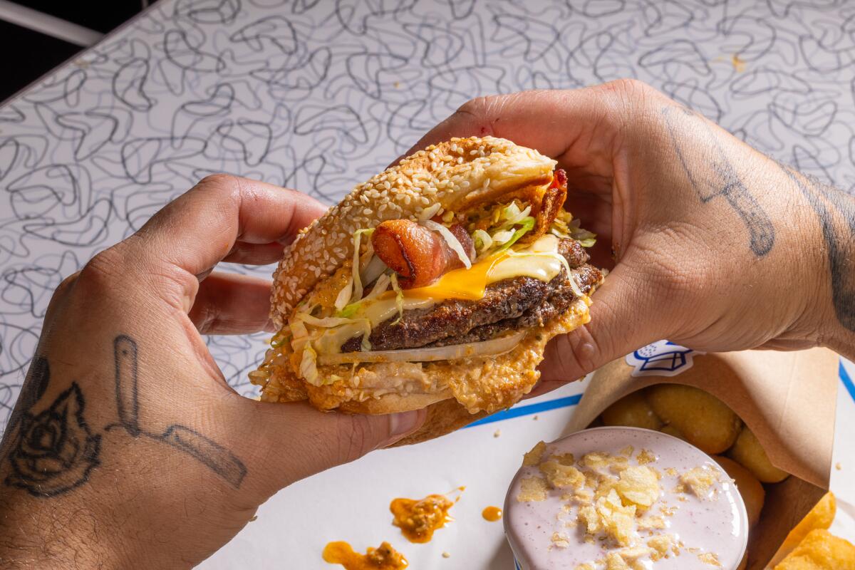 Tattooed hands holding a hamburger 