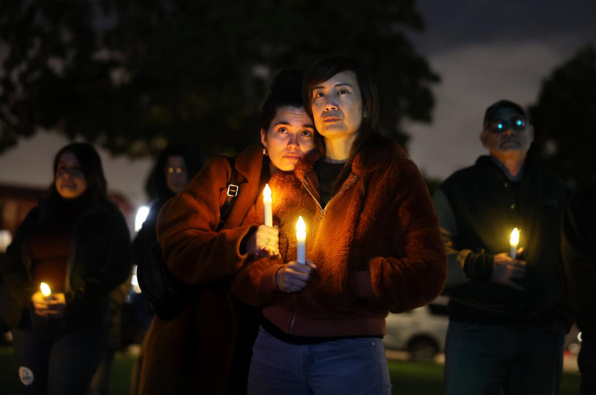 Two people stand together holding candles.