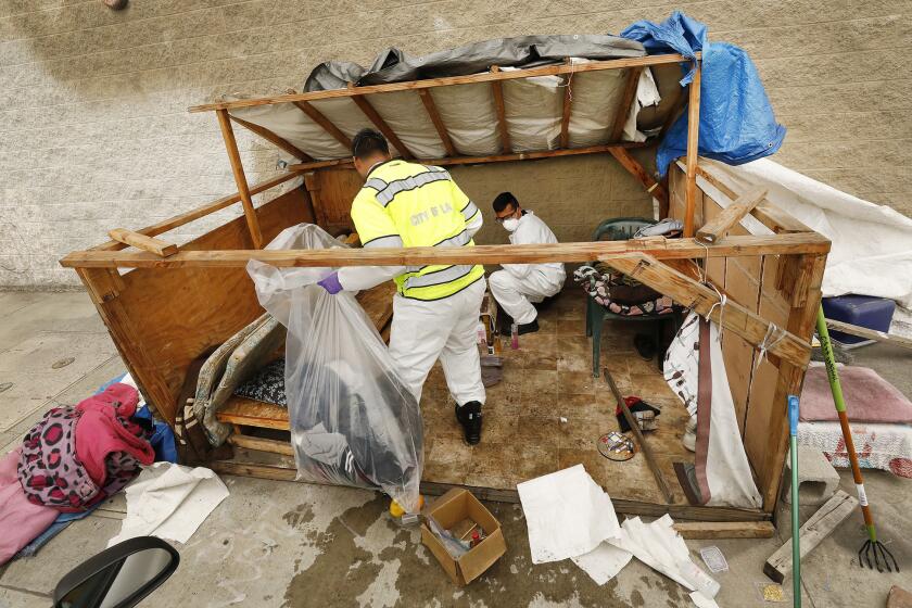 LOS ANGELES, CA - MAY 23, 2019 - Jesus Sanchez, left, and Javier Villarreal, right, with Watershed Protection Division of Los Angeles Bureau of Sanitation first secure the scene of hazardous materials as crews arrive to clean up the homeless encampment of Rickey Harris at 41st Place and Alameda on May 23, 2019 that has received complaints. There has been a uptick in complaints about homeless encampments that are filed through 311 over the last couple of years. They have gone up 166%. (Al Seib / Los Angeles Times)