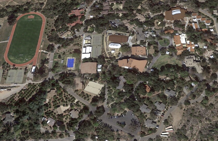 An aerial view of a school campus with tennis courts, a swimming pool and sports field