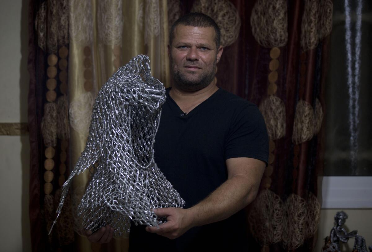 Palestinian artist Haitham Khateeb holds his sculpture depicting the late Palestinian leader, Yasser Arafat, with his famous keffiyeh.