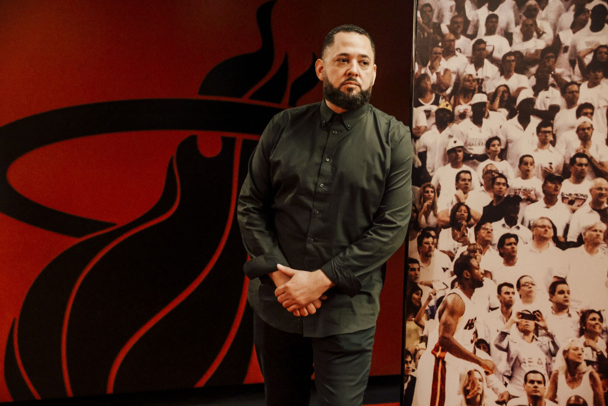 Jesse Saenz leans against wall decorated with Miami Heat logos and pictures of players at his nightclub