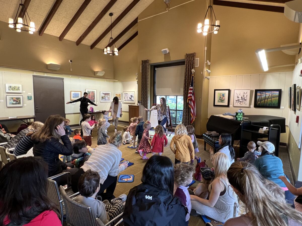 Children's services librarian Katia Graham (in front of the window) leads a Preschool Storytime about the letter Z.