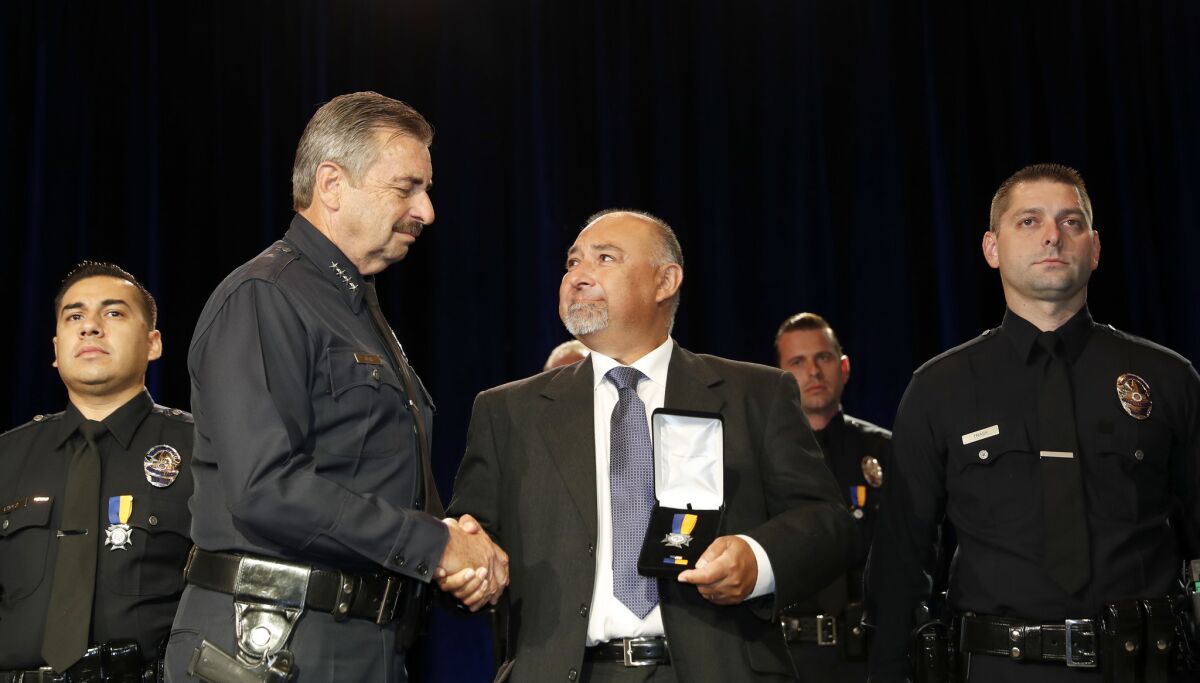 Greg Monroe, father of LAPD Officer Heather Monroe, accepts a Preservation of Life award from Chief Charlie Beck. Officer Monroe was killed in a car accident when she was off duty. Her partner, Officer Joel Trask, is on the right.