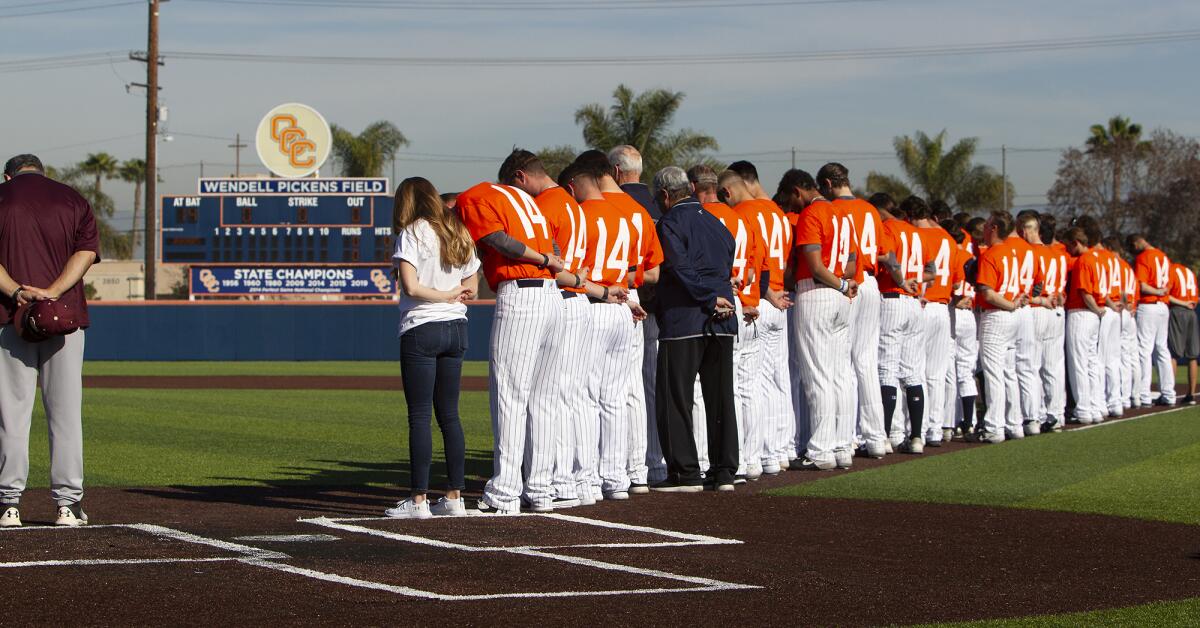 Members of the Orange Coast College baseball team bow their heads as they recognize late longtime coach John Altobelli and his family before Tuesday's season opener against Southwestern College in Costa Mesa. Altobelli, 56, his wife, Keri, 46, and daughter, Alyssa, 14, died in Sunday’s helicopter crash in Calabasas.