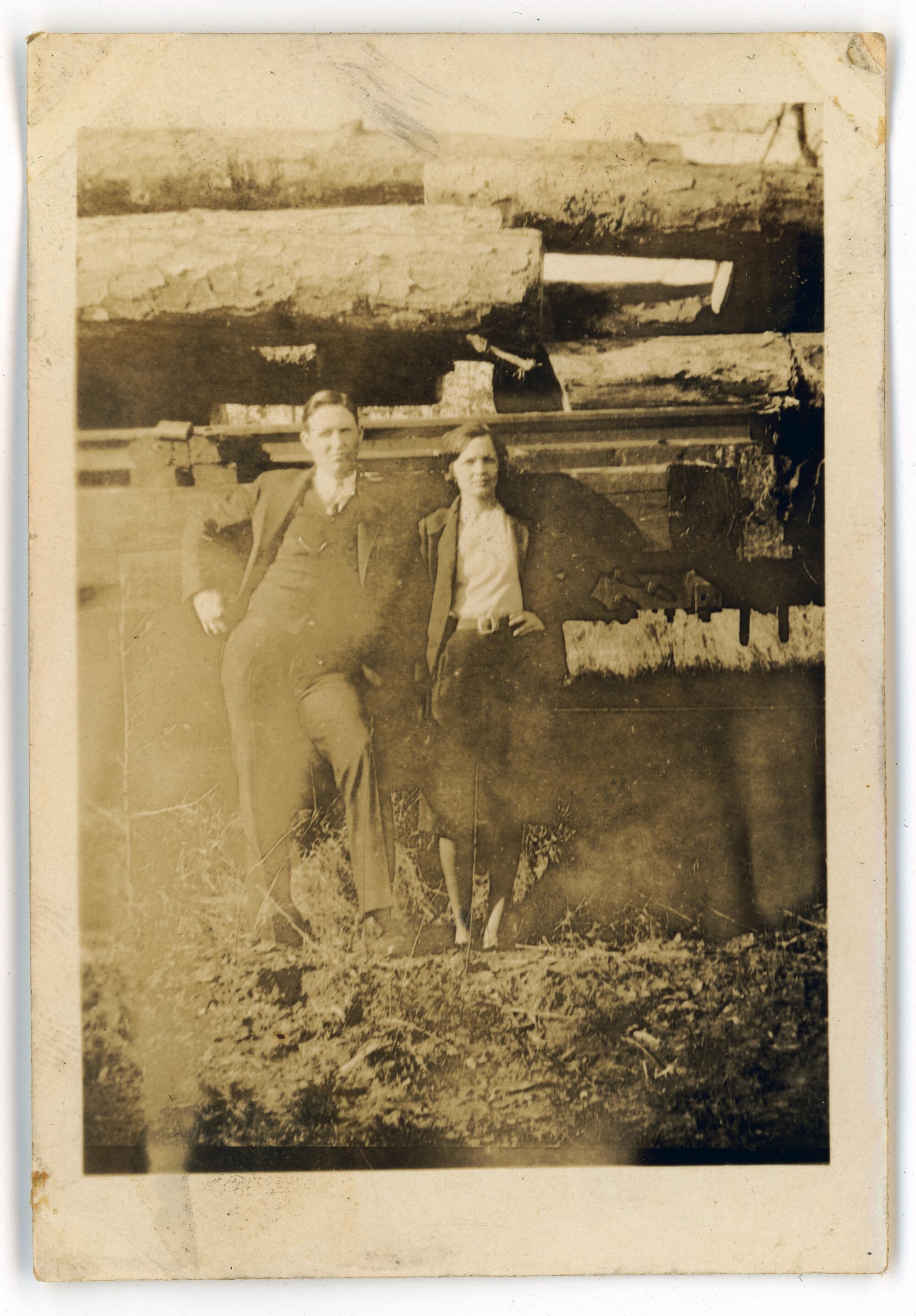 A man and a woman surrounded by farmland in a very old, yellowed photo.