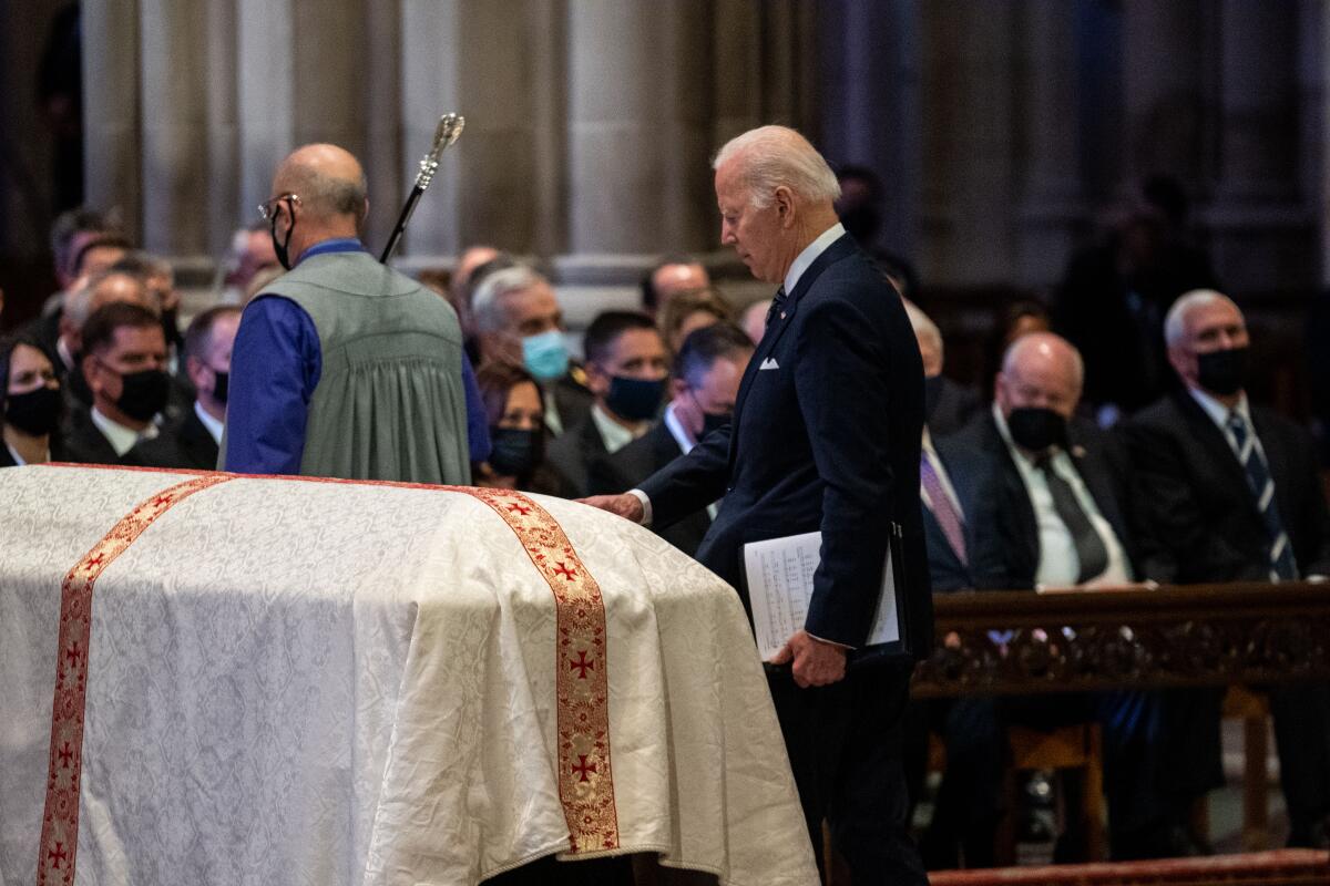 President Biden touches a casket draped with a white cloth