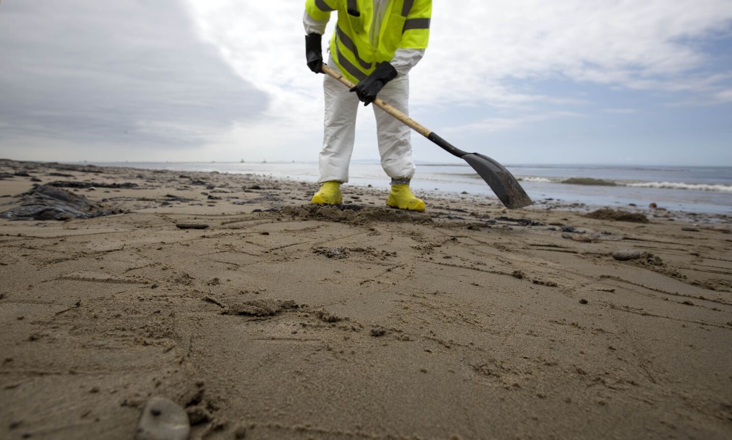 Patriot Environmental Services employee scrapes up oil-contaminated sand into small piles for removal on the shoreline at Refugio State Beach.
