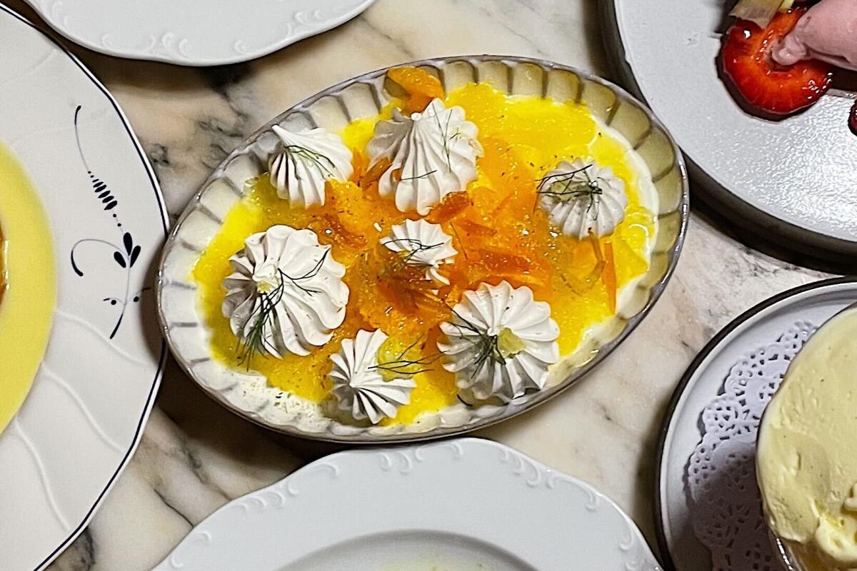 An overhead photo of a spread of desserts at Funke, with the meringata at center: meringue dollops atop orange granita