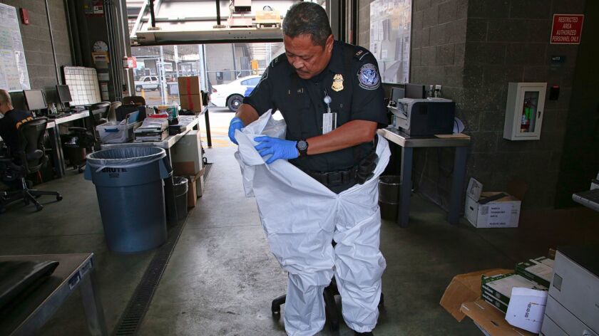 At the San Ysidro Port of Entry this week, U.S. Customs and Border Protection officer Rick Maravillas steps into a suit used to inspected shipments containing illegal drugs. The full gear includes the safety suit, two pairs of gloves, eye goggles and a full face shield.