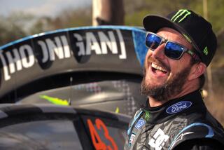 Head and shoulders view of Ken Block, wearing a hat and sunglasses, laughing.