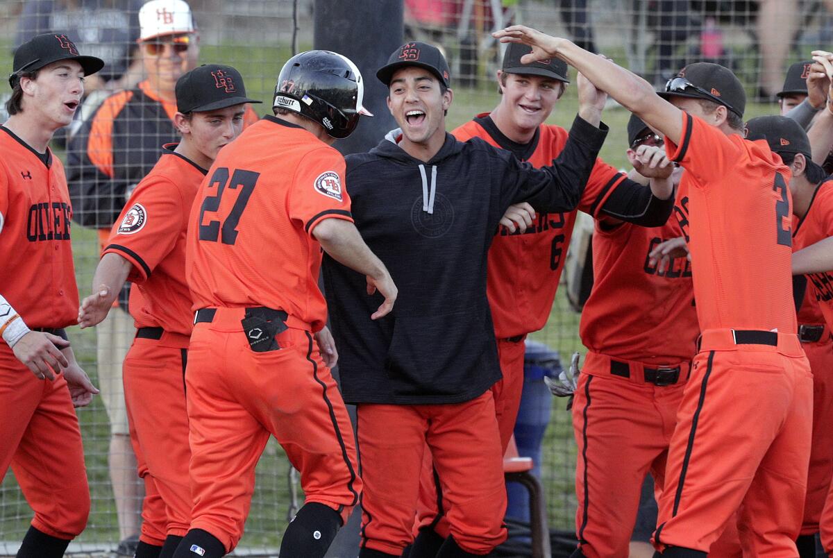 Huntington Beach's Jake Vogel (27) is congratulated by teammates after hitting a three-run home run against Harvard-Westlake on Feb. 26. The Oilers' season is postponed indefinitely due to the coronavirus.