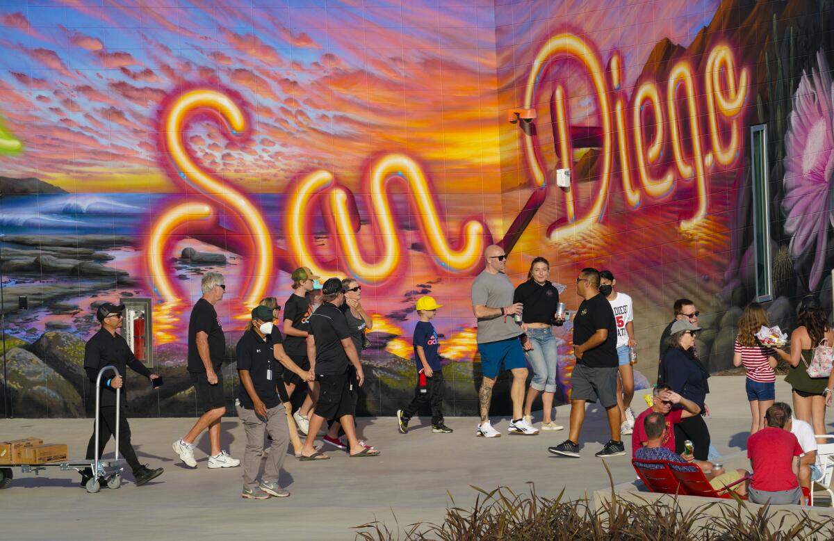 Aztecs fans walk pass one of the large scale murals painted on the walls at Snapdragon Stadium.