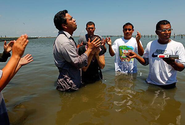 In the bay waters of Grand Isle, La., Pastor Vidal Galvez baptizes two members of his church from Gretna, La., as the oil spill swirls offshore in the Gulf of Mexico. Full story