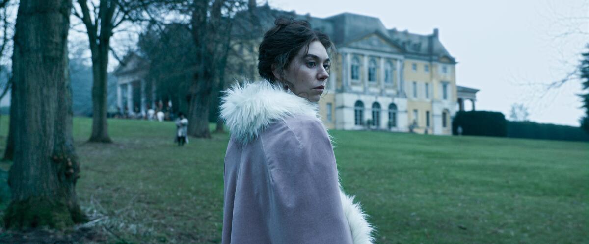 A woman in a purple robe stands alone outside.